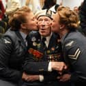 Alec Penstone in Navy uniform being kissed on both cheeks by two women in uniform