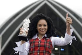 Kanya King giving a thumbs up with one hand and holding a Mobo Award in her other