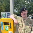 Jordan Kerr next to a defibrillator at Drumchapel station