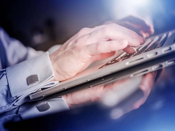 Man's hands typing on a laptop keyboard