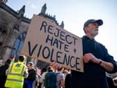 A man holding a sign reading 'Reject hate and violence'
