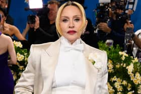 Madonna posing for photos at a red carpet event, wearing an ivory suit