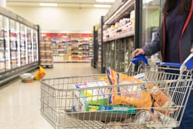 A shopper with a trolley filled with groceries at a supermarket