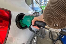 A woman putting putting unleaded petrol into her car at a petrol station in London