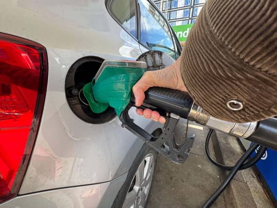 A woman putting putting unleaded petrol into her car at a petrol station in London
