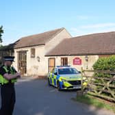 Police and police cars outside a farm-style building