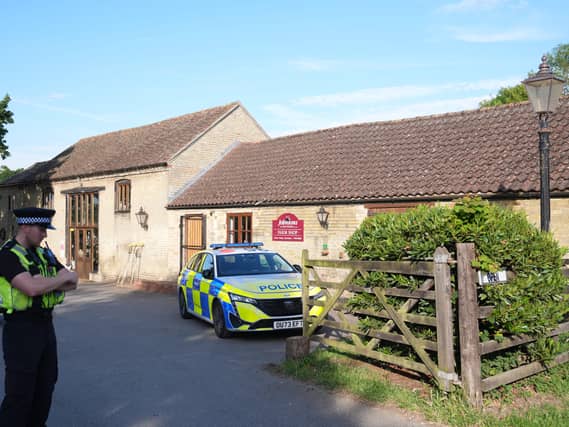 Police and police cars outside a farm-style building