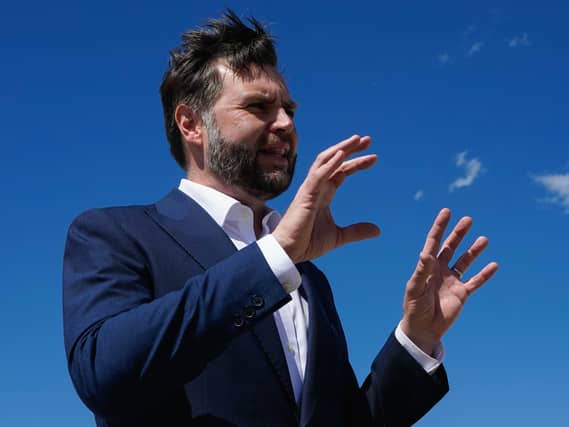 JD Vance gesturing with his hands while speaking, under a blue sky