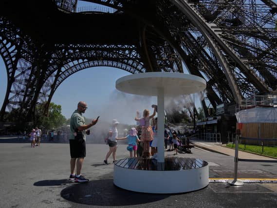 People cool off in a water spray near the Eiffel Tower in Paris