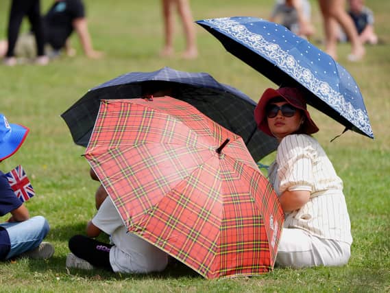 A family shelter under umbrellas during an Armed Forces Day event in Aldershot, Hampshire, on Saturday