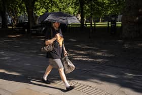 A person holds an umbrella up for shade on an early morning journey on Friday