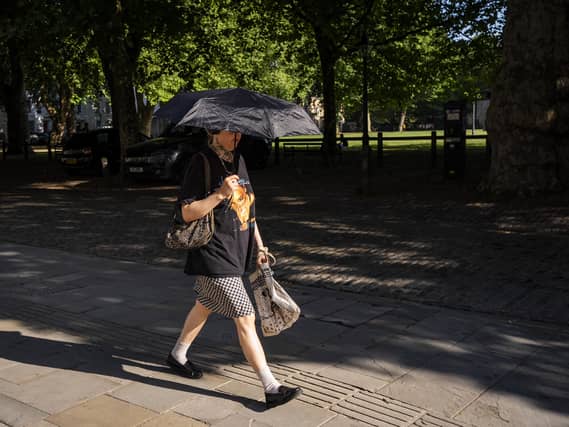 A person holds an umbrella up for shade on an early morning journey on Friday