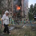 A woman walks past a burning building after a Russian missile attack in Kyiv