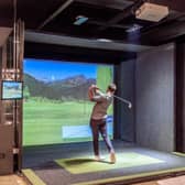 A man plays a game of golf on a virtual reality machine