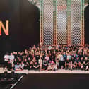 Harry Styles holding his Guinness World Records certificate on stage surrounded by members of his team
