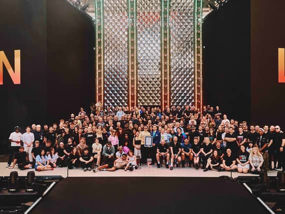 Harry Styles holding his Guinness World Records certificate on stage surrounded by members of his team