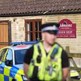 An out-of-focus police officer in front of Johnsons of Old Hurst zoo