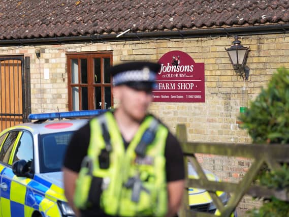 An out-of-focus police officer in front of Johnsons of Old Hurst zoo