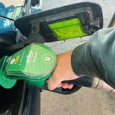A person fills a car with petrol at a service station