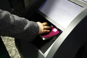 A hand holding a passport onto a scanner at an e-gate