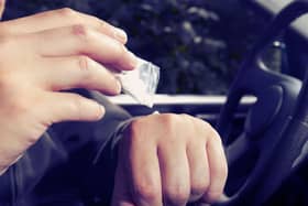 A male model taking drugs behind the wheel of a car