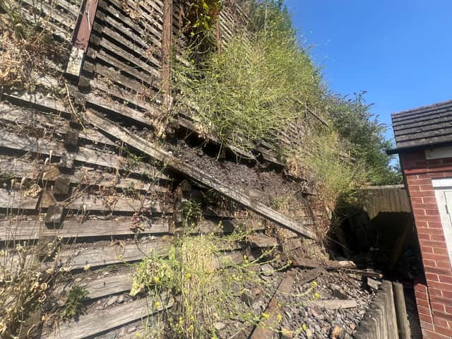 The wooden wall behind the Goodrich Mews estate is visibly falling into disrepair