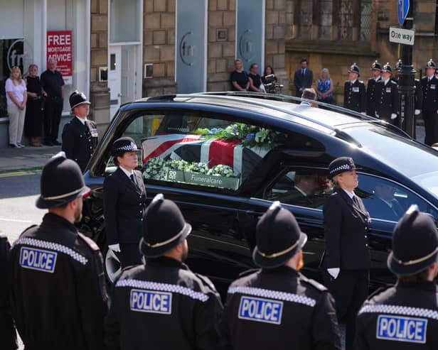Police stand in line as a coffin in a hearse passes