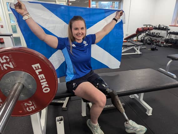 Hope Gordon smiling while holding up a Scottish flag