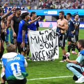 Argentina players hold a banner on the pitch