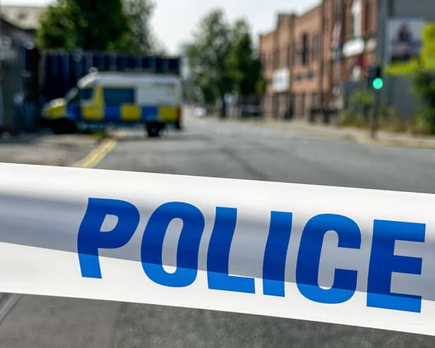 Police tape in the foreground and a police van in the background on a residential street
