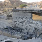 People stand on a bridge destroyed after a strike in Hormozgan province, southern Iran