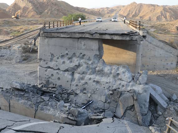 People stand on a bridge destroyed after a strike in Hormozgan province, southern Iran