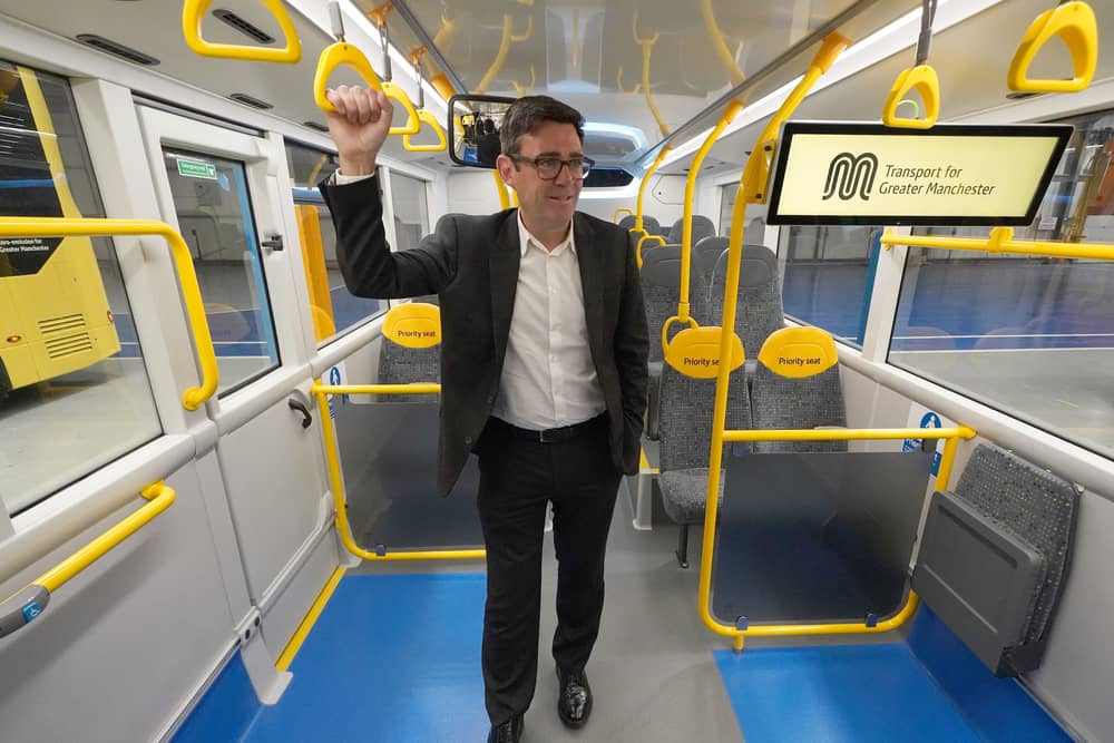 Andy Burnham standing on a bus