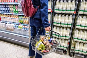 A woman holds a shopping basket in the aisle of a supermarket