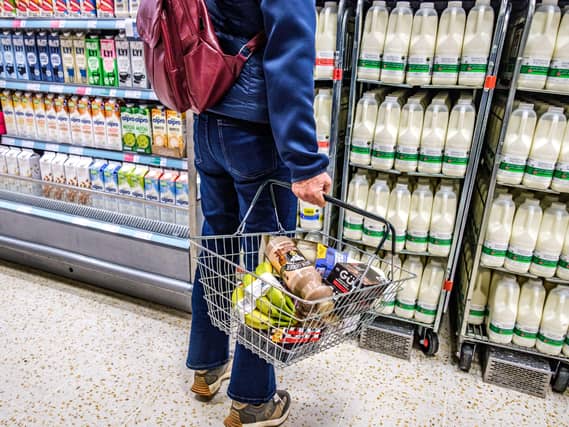 A woman holds a shopping basket in the aisle of a supermarket