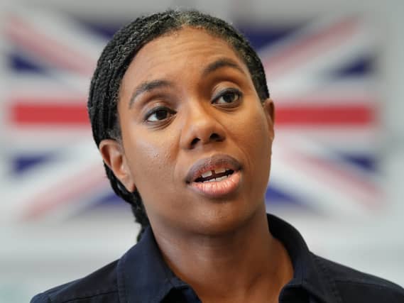 Headshot of Kemi Badenoch speaking, with a British flag in the background
