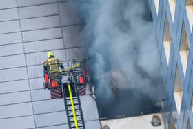 Firefighters in a cherrypicker as smoke pours out of a building