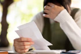A woman with their hand on their head in distress while reading paperwork