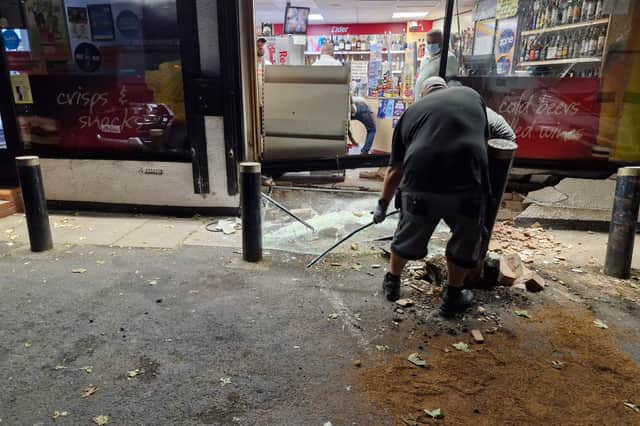 People cleaning up debris at the store after the crash in Cannock