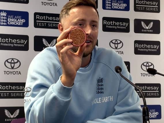 Ollie Robinson showing a cricket ball sliced in two