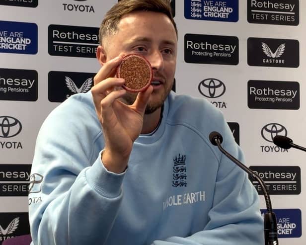 Ollie Robinson showing a cricket ball sliced in two