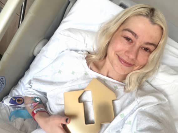 Phoebe Bridgers smiling while lying in a hospital bed