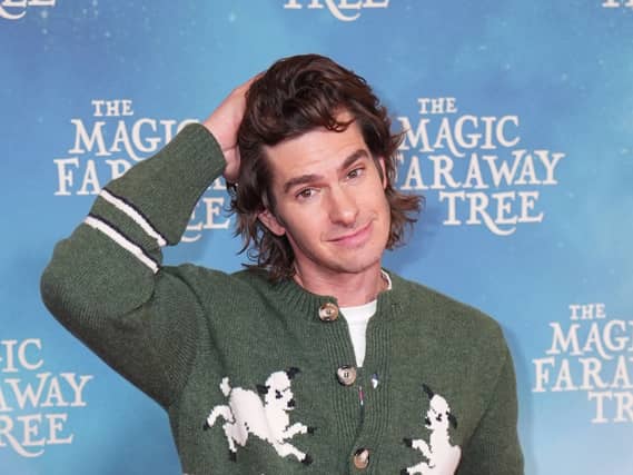 Andrew Garfield wearing a green cardigan with palm trees with his right arm raised over his head at The Magic Faraway Tree special screening