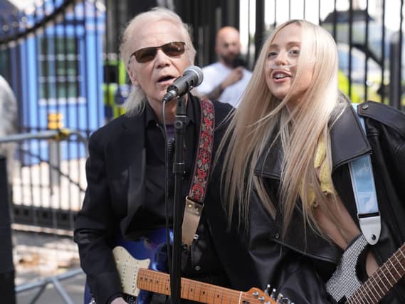 Brian Hyland and Ashleigh Harley playing guitars and singing outside Downing Street.
