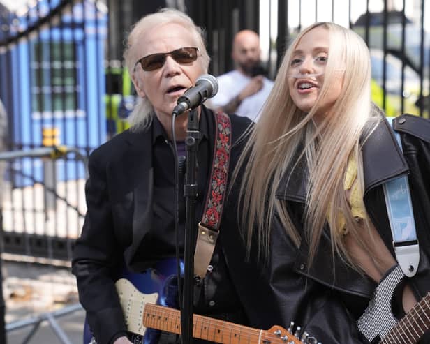 Brian Hyland and Ashleigh Harley playing guitars and singing outside Downing Street.