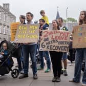 Protesters holding up placards with comments including 'real men care for their children' and 'invest in families, invest in the future'