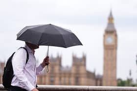 A person uses an umbrella while out walking, with the Houses of Parliament in the background