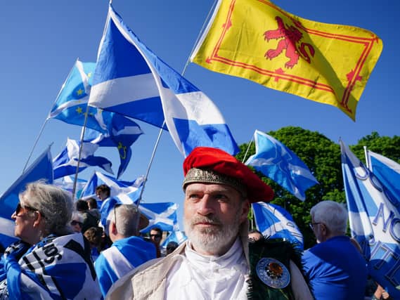 Independence supporters waving Scottish flags, standing outside under blue skies