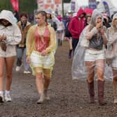 Festivalgoers shelter from the rain in plastic ponchos as they walk through the muddy site at the Reading Festival at Little John’s Farm, Reading, Berkshire.