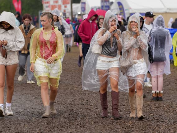 Festivalgoers shelter from the rain in plastic ponchos as they walk through the muddy site at the Reading Festival at Little John’s Farm, Reading, Berkshire.